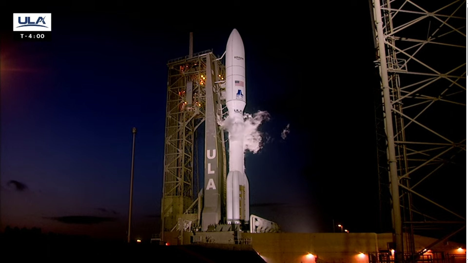 A gold and white atlas v rocket on the launch pad carrying 28 Amazon Kuiper satellites