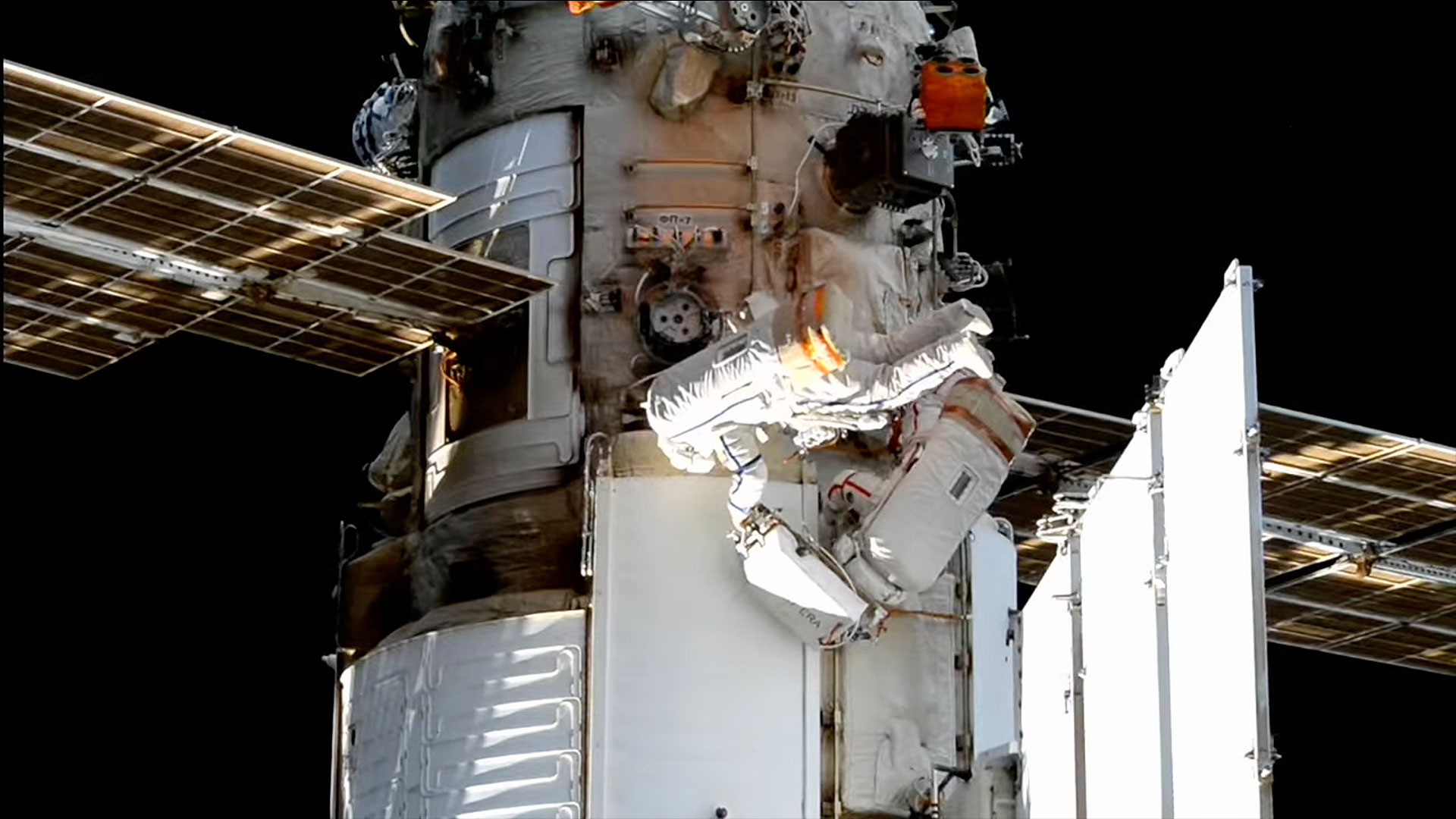 two spacesuited cosmonauts work outside a space station during a spacewalk